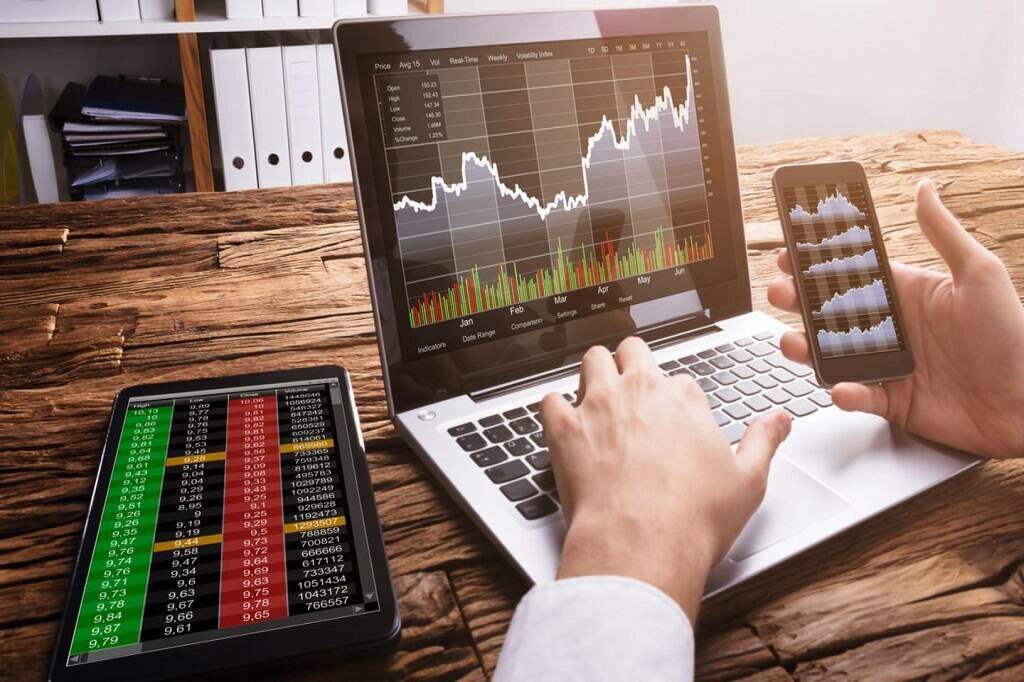 O que é e como fazer uma gestão de banca? Dicas e métodos infalíveis! 6 Apostador em frente às telas do notebook, celular e tablet, enquanto faz a gestao de banca