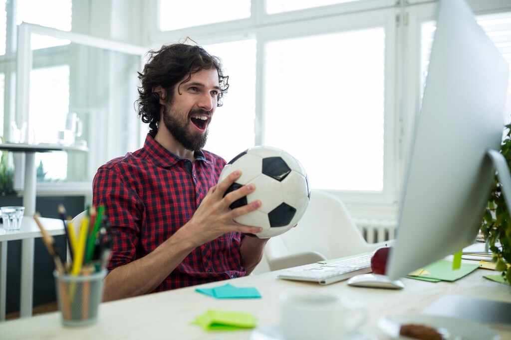 O que é uma aposta acumulada? Entenda como funciona e dicas para apostar 2 apostador comemora uma aposta acumulada vitoriosa, segurando uma bola de futebol na mao